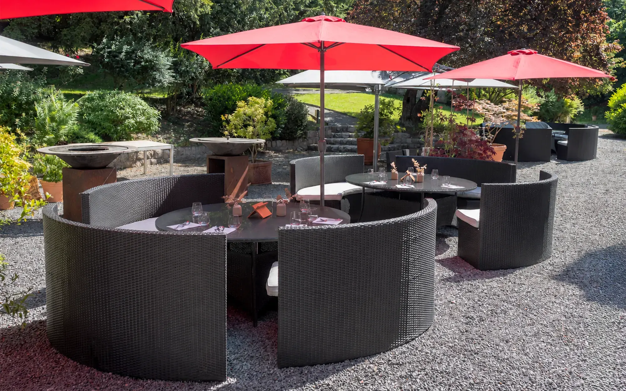 Het terras van het domein met tafels onder rode parasols